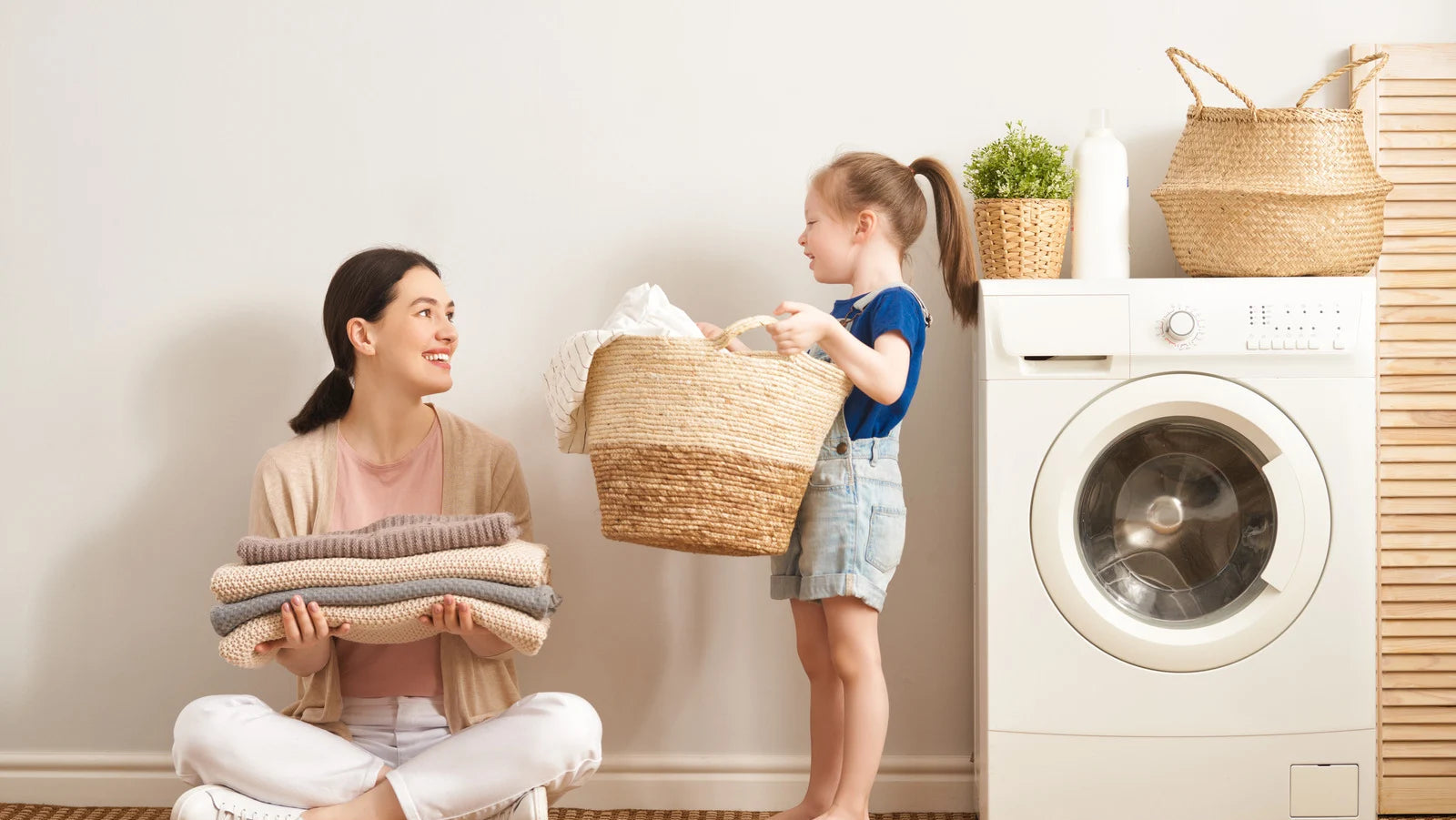 Woman and child in a laundry room with washing machine and laundry basket